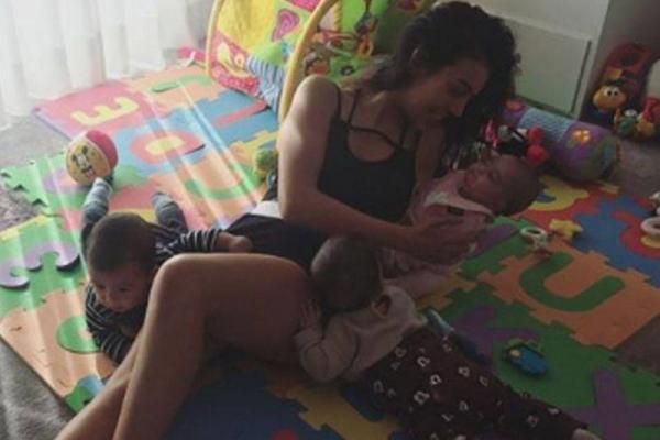 Georgina terlihat sedang berbaring sambil memeluk Alana, sementara si kembar sedang asyik bermain-main