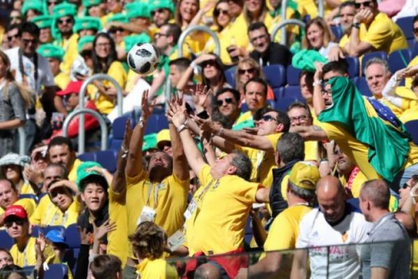 Bernyanyi di atas bus beratap terbuka di tengah kerumunan orang yang memakai baju hijau kuning, warna lambang Brazil.