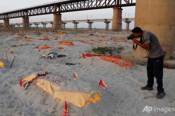 Pada Jumat (14/5), hujan menyingkap kain penutup tubuh yang terkubur di kuburan pasir dangkal di tepi sungai di Prayagraj, sebuah kota di negara bagian Uttar Pradesh.