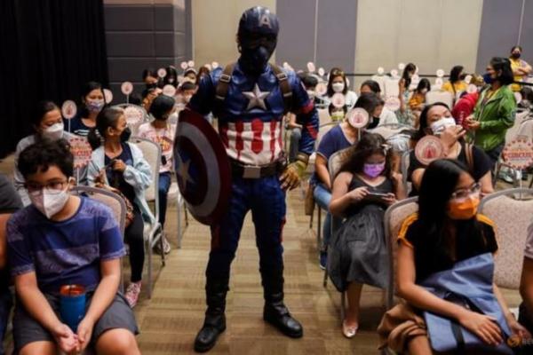 Captain America terlihat berpose bersama anak-anak yang berusia 5 hingga 11 tahun setelah menerima vaksin Pfizer di sebuah mal di Taguig City, Metro Manila, Filipina, 7 Februari 2022.
