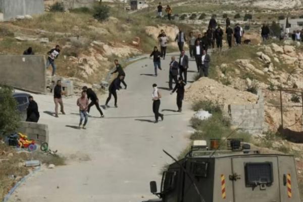 Warga Palestina melemparkan batu ke pasukan Israel yang menembakkan gas air mata ke arah mereka saat buldoser bergerak di lokasi di desa Jabbet al-Dhib dekat Bethlehem.